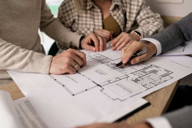 three people looking at the blueprint of a property