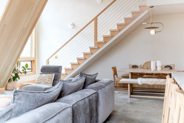 inside living room with stairs and grey couch