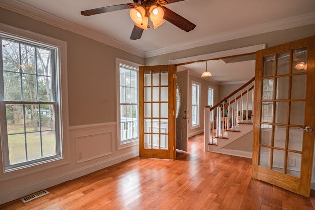 An empty living room with a ceiling fan.